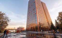Верхние этажи медной башни ЖК АУРА утром — Москва-река и силуэт Москва-Сити на горизонте